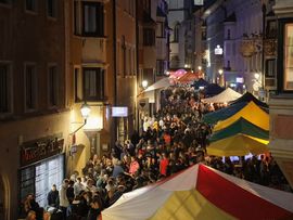 Besucherinnen und Besucher feiern vor einer Bühne bei einem Abendkonzert. Mehrere Menschen halten ihre Smartphones mit eingeschaltetem Licht in die Höhe und genießen die Festivalstimmung.