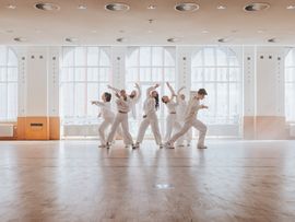 Tänzer in weißer Kleidung in einem Saal